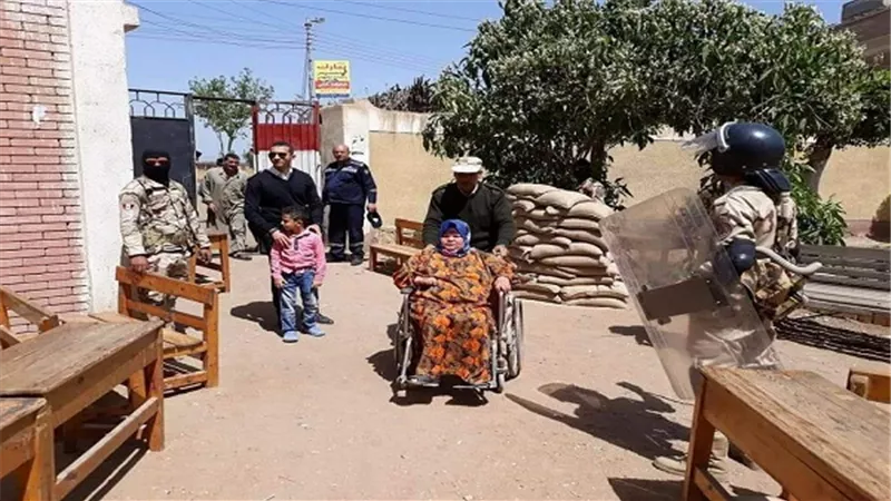 مساعدة سيدة من ذوي الاحتياجات الخاصة أثناء الإدلاء بصوتها بمدرسة بكفر شكر